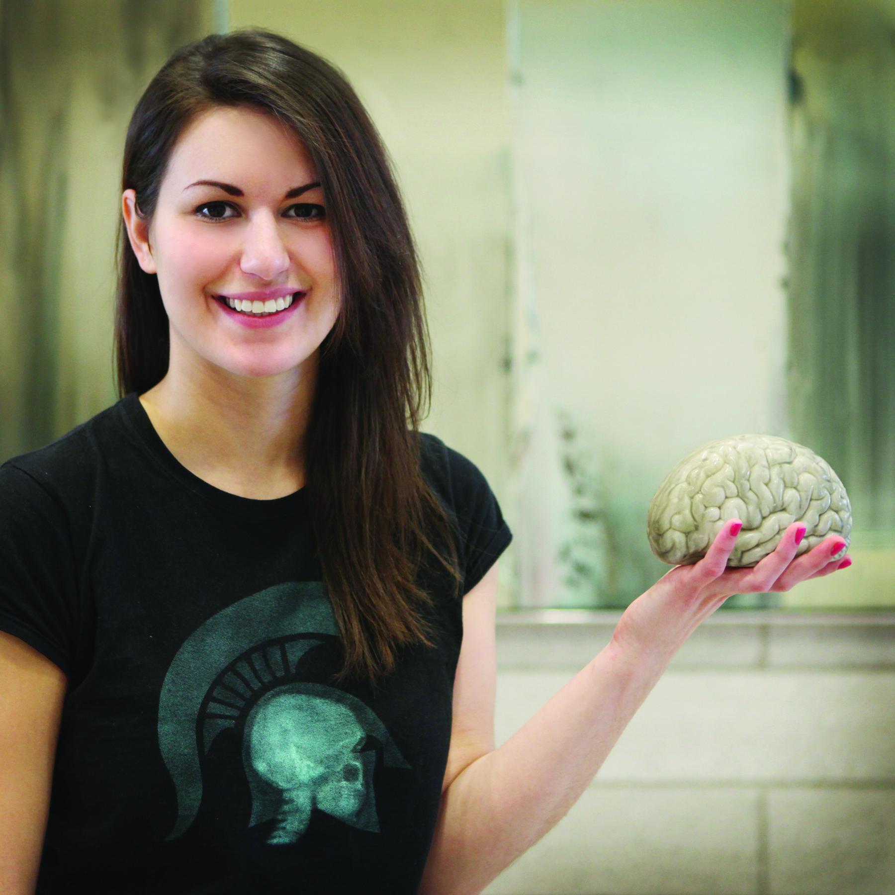 Younger woman holding a model brain.